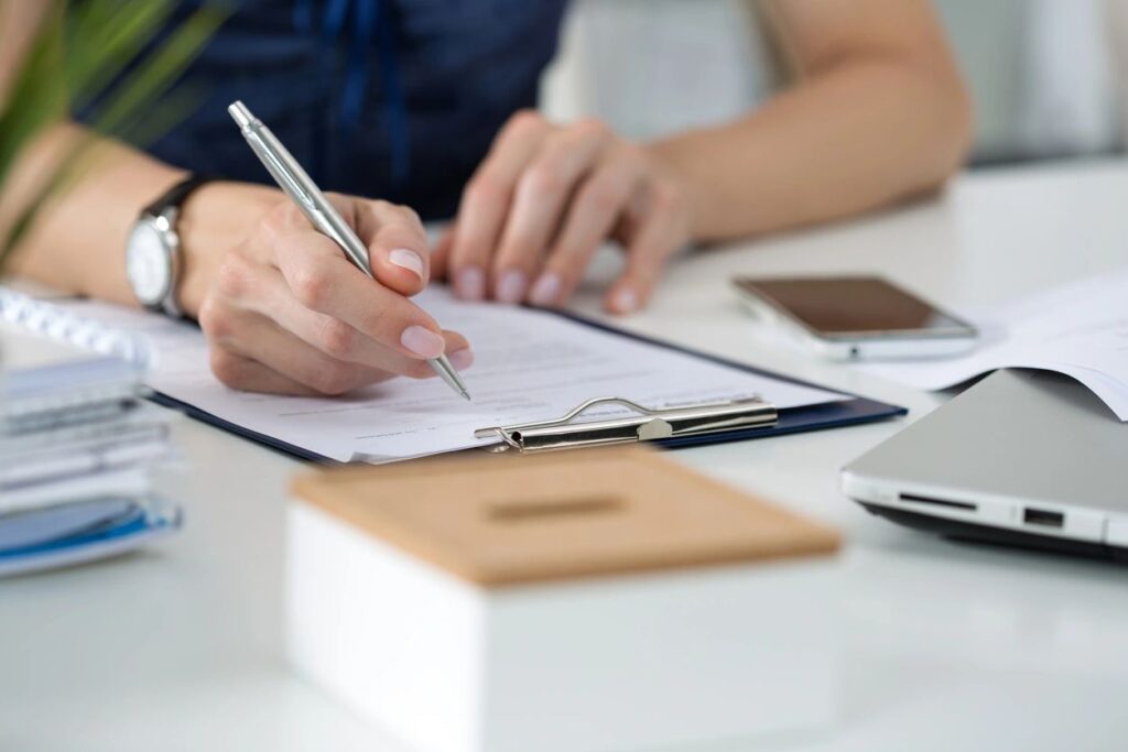 Person filling out form on clipboard